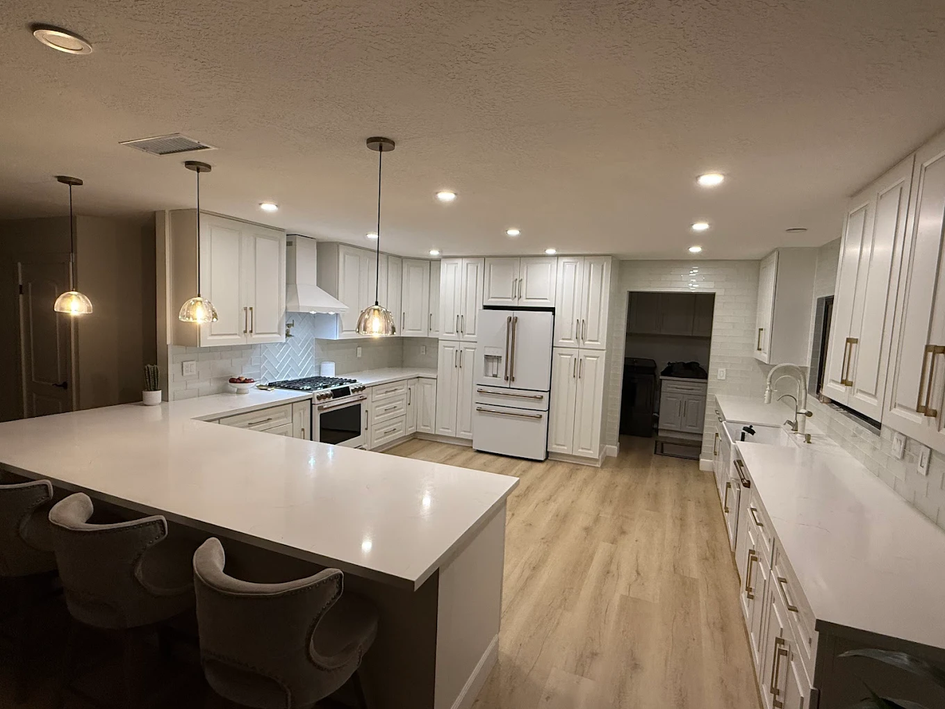 Remodeled kitchen with an island, white cabinets, long countertops and recessed lighting