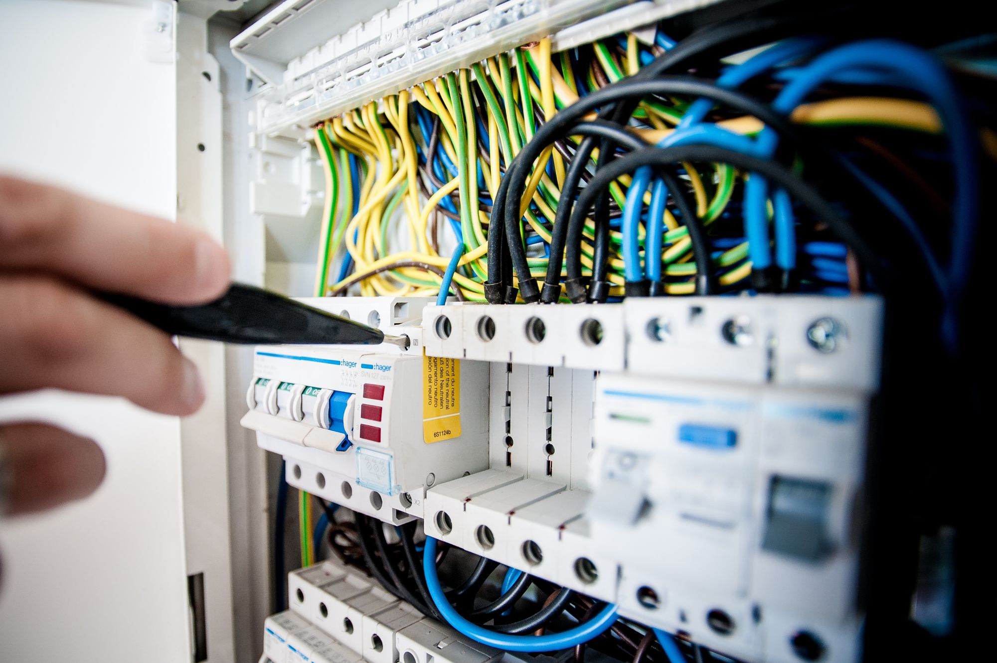 Electrician correcting wiring inside a commercial breaker panel to meet electrical code