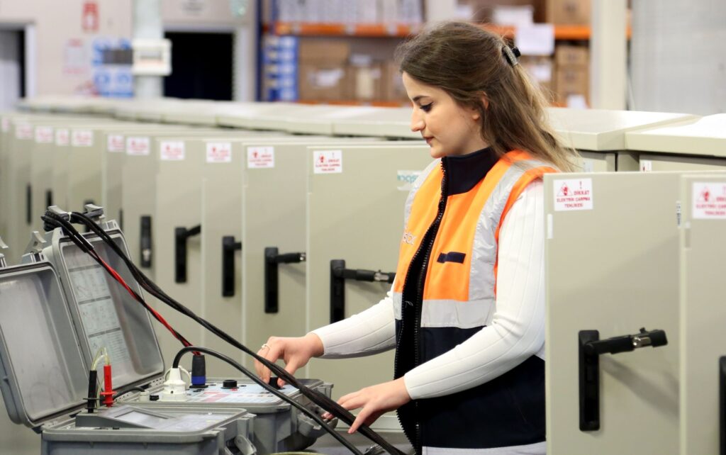 Technician in safety gear testing commercial electrical panels during a compliance inspection
