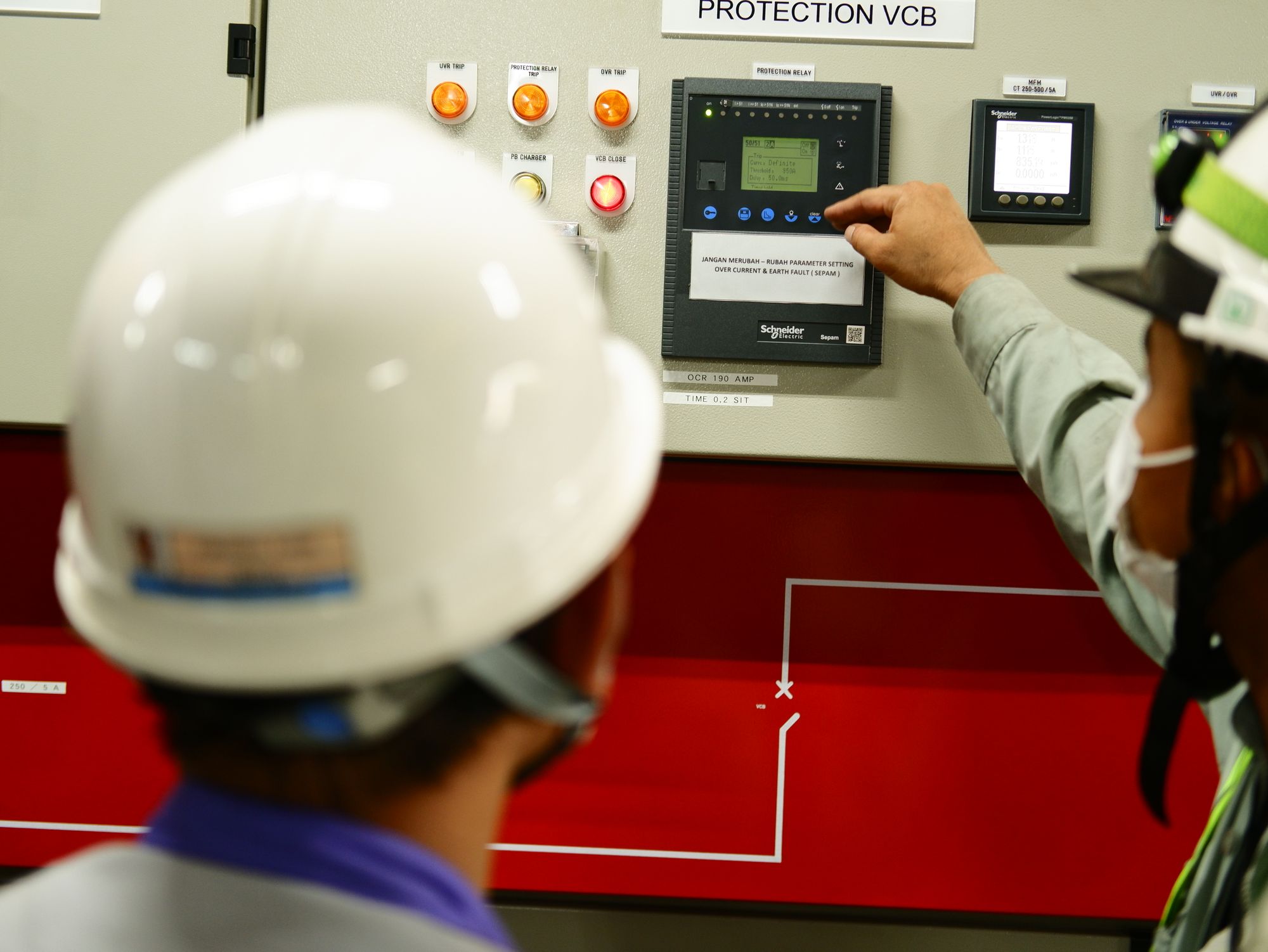 Engineers operating a commercial control panel as part of the electrical code correction process