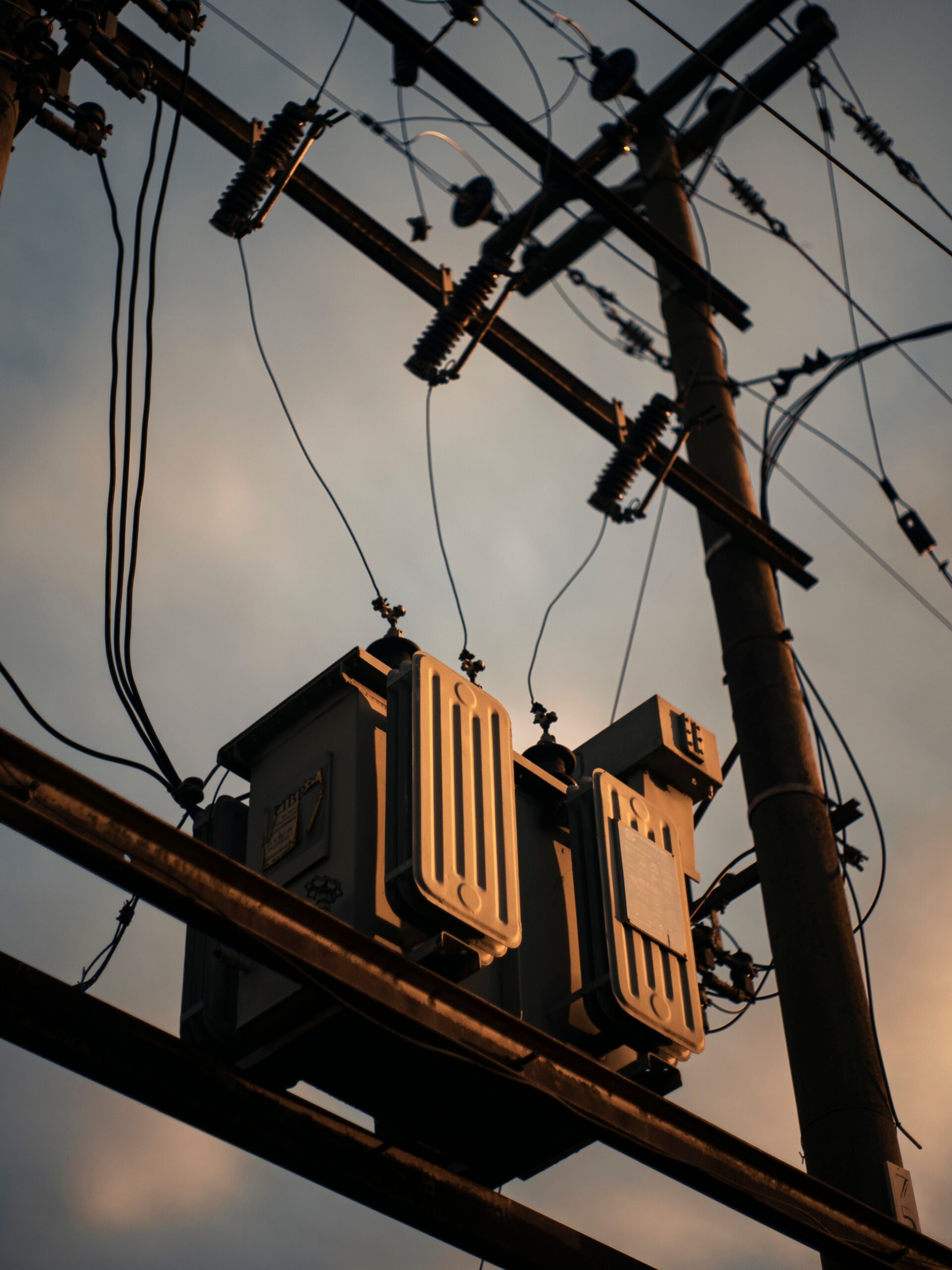 A dramatic shot of a transmission tower with power lines silhouetted against a sunset sky.