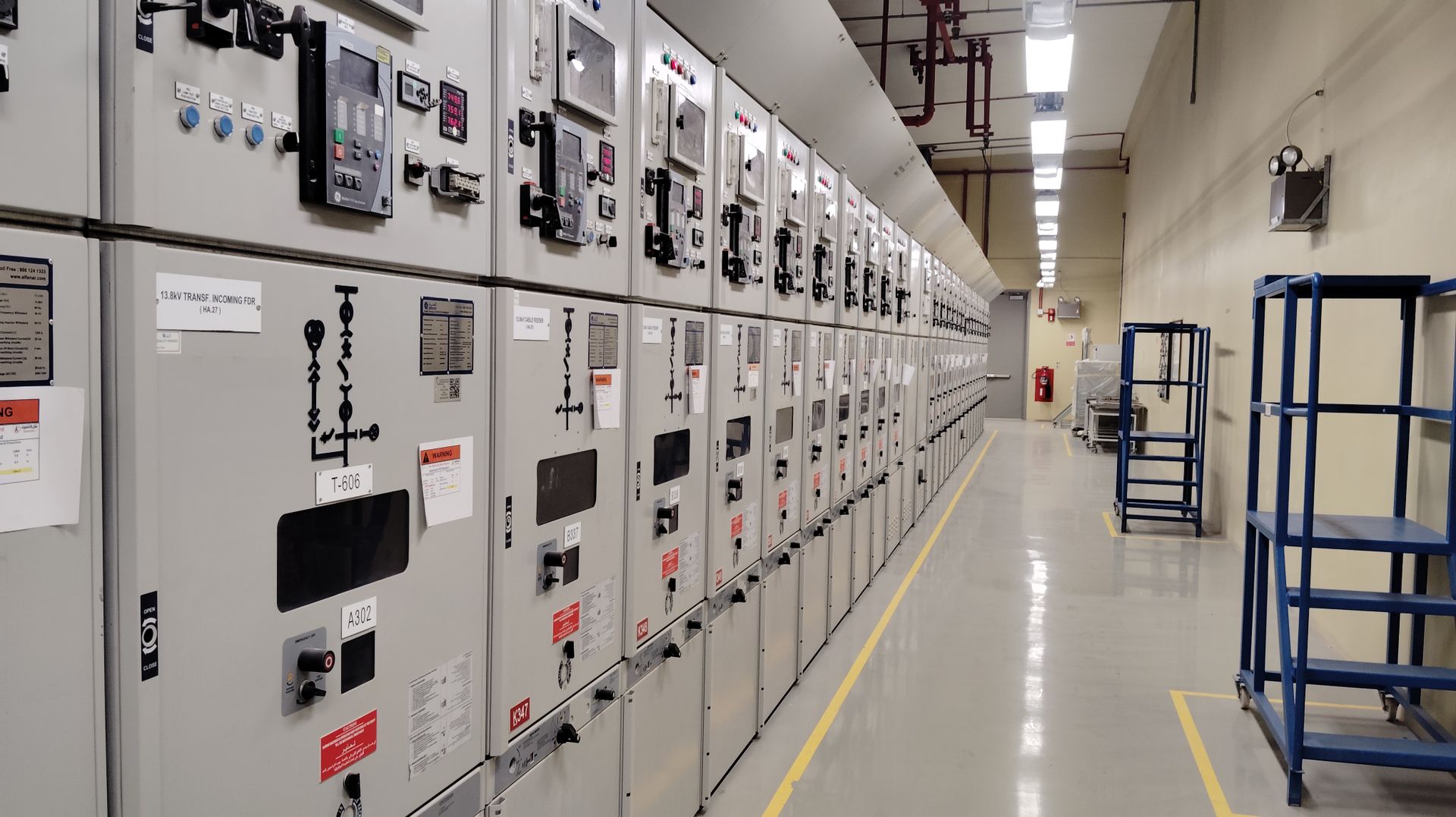 Row of commercial medium voltage switchgear cubicles with arc flash warning labels in a facility electrical room